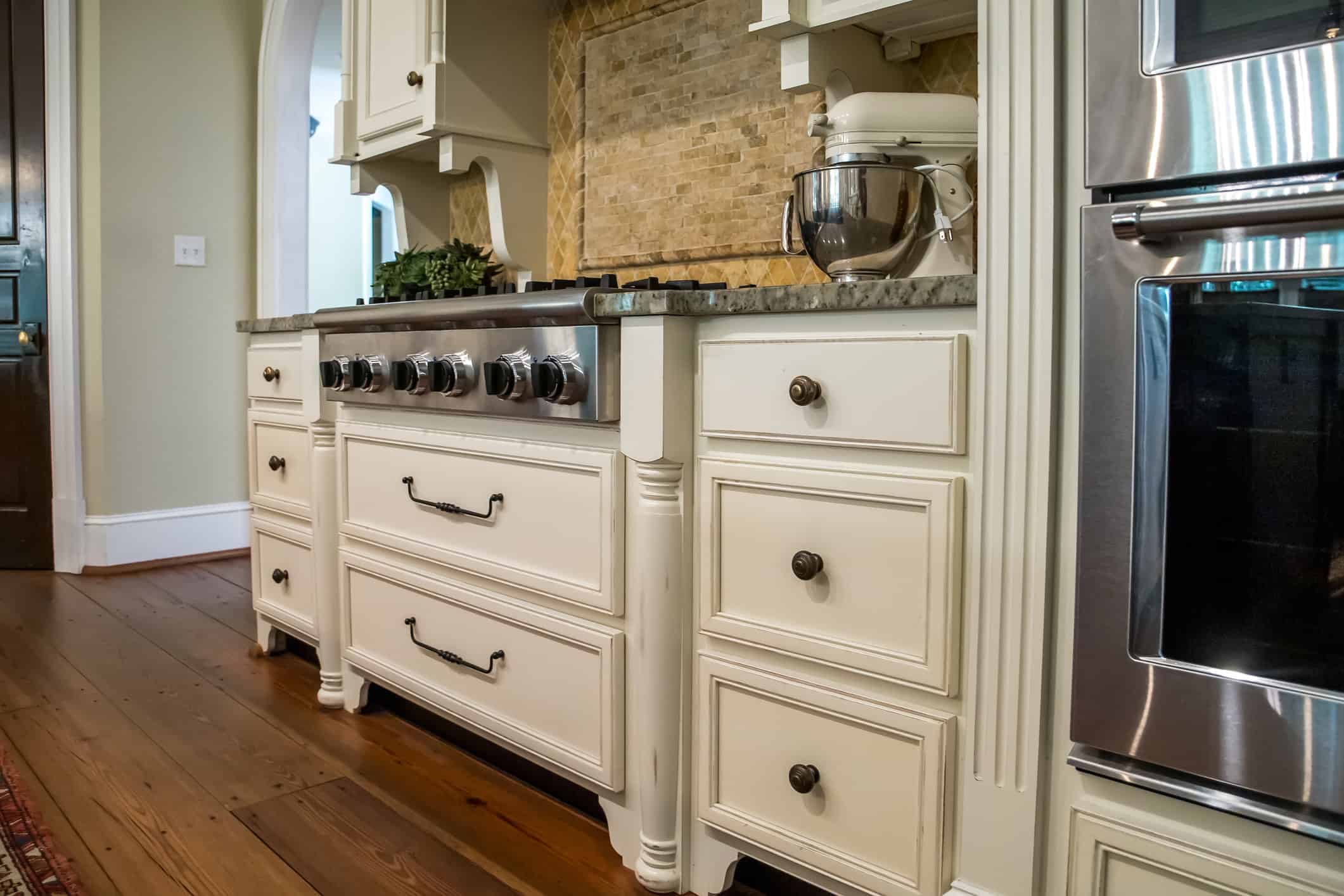low view of kitchen with hardwood floors and custom cabinets and stove and runner rug